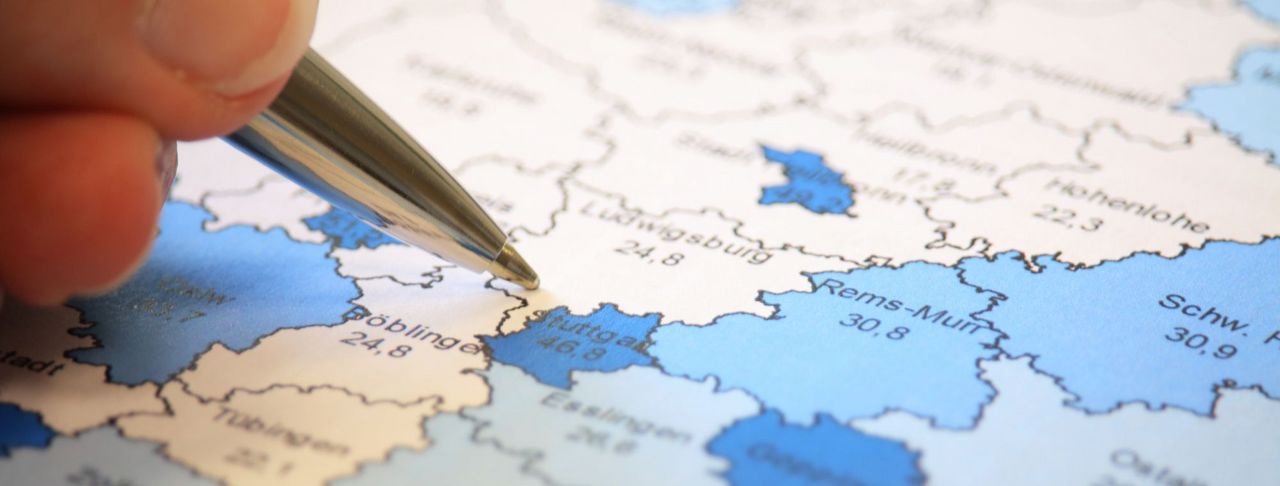 Eine Hand zeigt mit Stift auf eine Landkarte